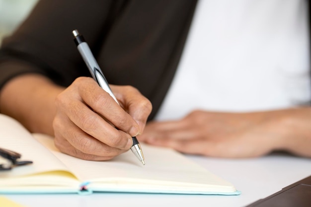 Student studying exam preparation holding pen taking notes in diary selective focus