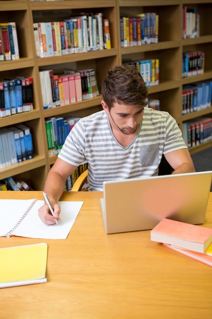 Студент, обучающийся в библиотеке с ноутбуком