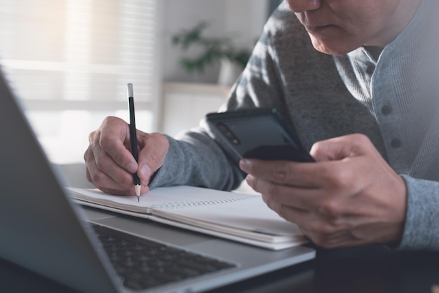 Foto studente che studia in classe online tramite laptop e tiene lezioni su un blocco note cartaceo