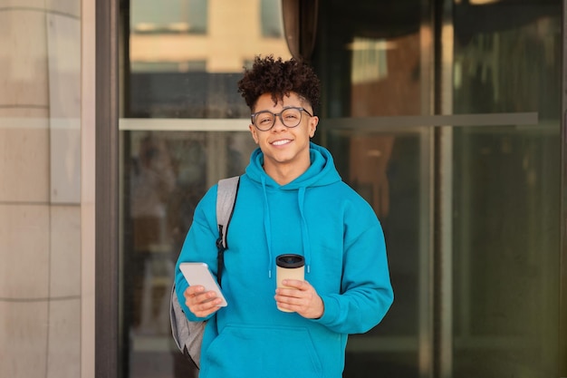 Student takes coffee break browsing on smartphone in urban setting