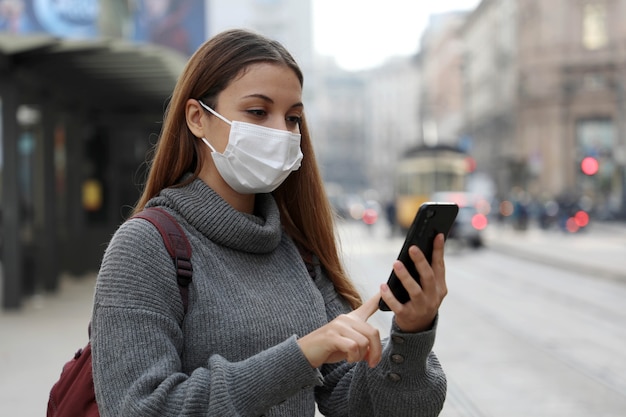 Ragazza dell'adolescente dell'allievo con la mascherina protettiva che paga il biglietto di trasporto in linea