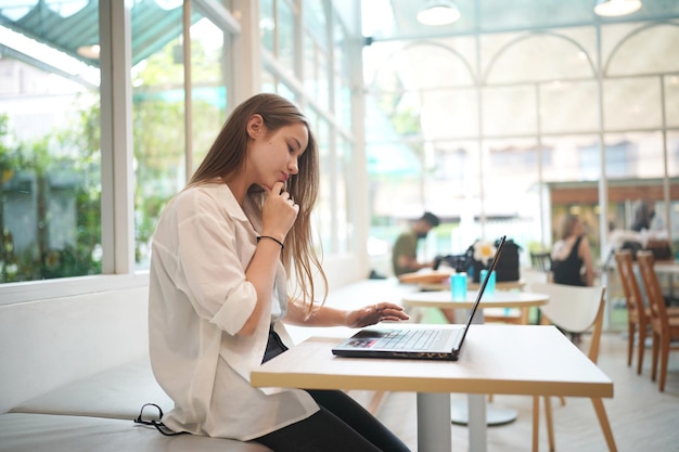 Student Texting Message in laptop at cafe