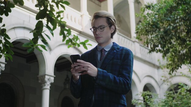 Student typing on smartphone businessman reading good news on
phone outdoors