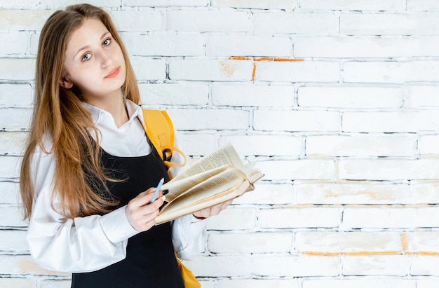 Student in a uniform holding her book and looking at the objective High quality photo