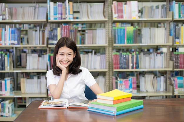Studente in uniforme libro di lettura per l'apprendimento in biblioteca all'università.