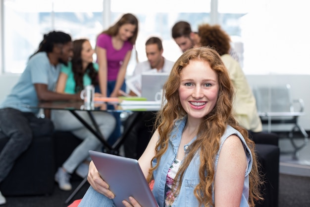 Student using digital tablet with friends in background