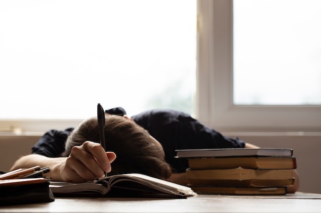 Student viel in slaap voor huiswerk op zonnige achtergrond