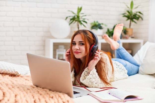 Student vrouw is blij om te luisteren naar muziek met een koptelefoon via het internet