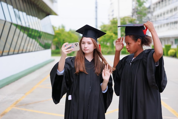 Studente che indossa un abito e fa foto con lo smartphone che si laurea buon successo e celebrazione del laureato congratulazioni