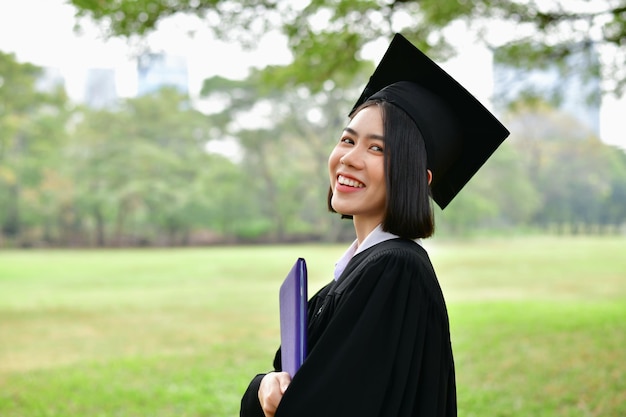 공원 에서 경기장 에 서 있는 학생 이 졸업 의복 을 입고 있다