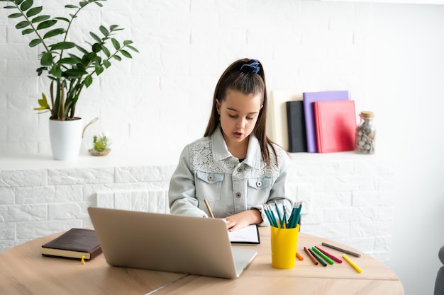 Student weinig schoolmeisje huiswerk op laptop computer zilveren achtergrond