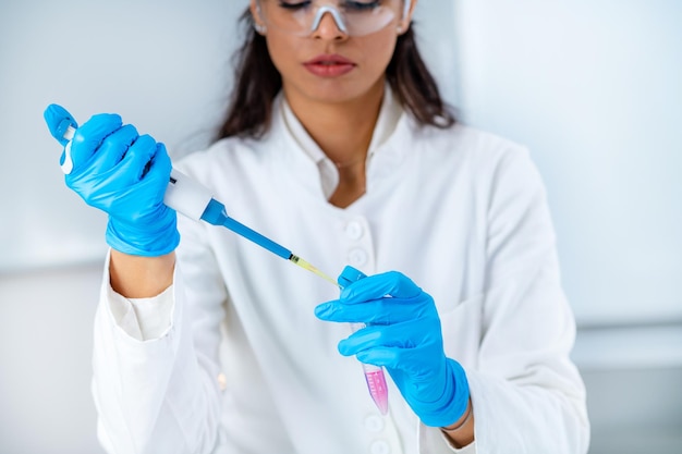 Student in White Coat Working in Research Laboratory Using Micro Pipette and Test Tube