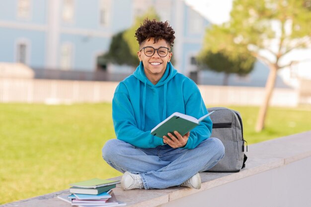 Student with book sitting outdoors on campus