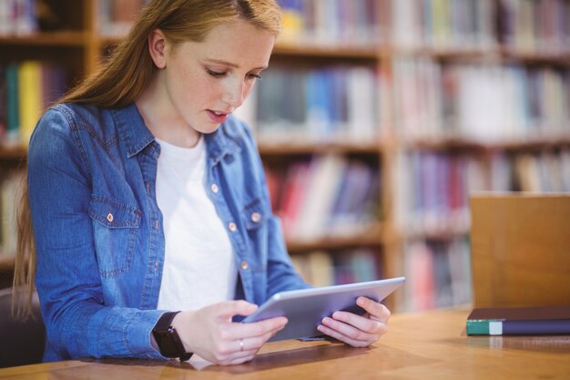 Фото Студент с помощью smartwatch с использованием планшета в библиотеке