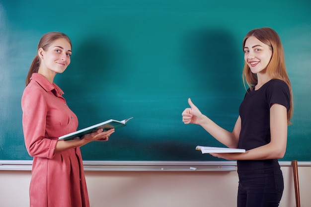 Student with teacher stand in the classroom at the blackboard. Back to school.