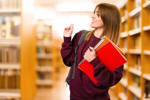 Student woman pointing back on unfocused background. back to school