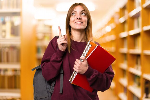 Student woman pointing up on unfocused background. back to school