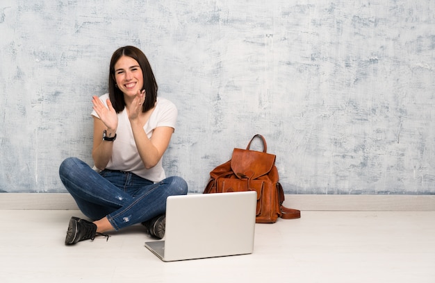 Student woman sitting on the floor applauding after presentation in a conference