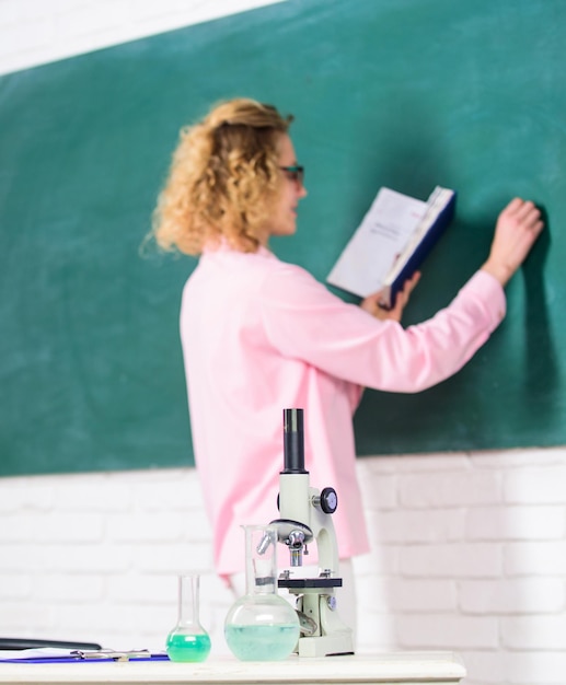 Foto studente che scrive lavagna sfocata concetto di biologia laboratorio di biologia microbiologia e bioingegneria tubi di formica del microscopio con liquidi chimici sul tavolo insegnante di biologia della scuola messa a fuoco selettiva