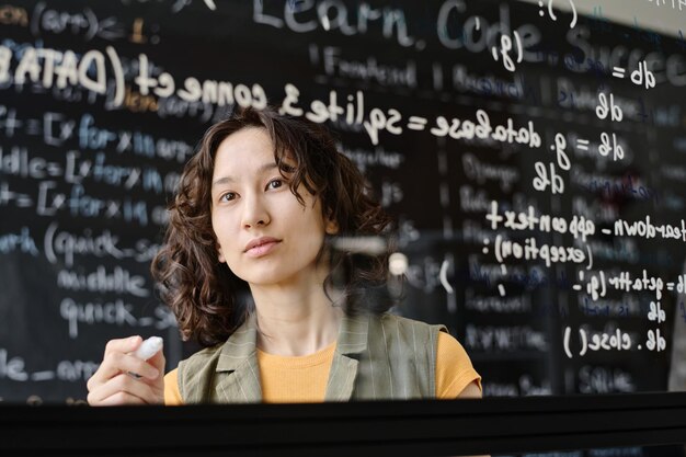 Student writing codes on blackboard during IT lesson in the classroom