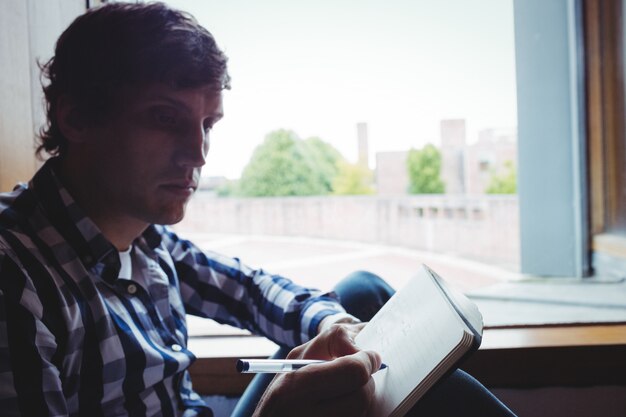 Student writing notes near window