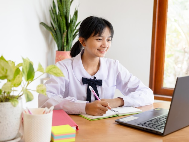 写真 家でラップトップで勉強する学生の少女はオンラインで