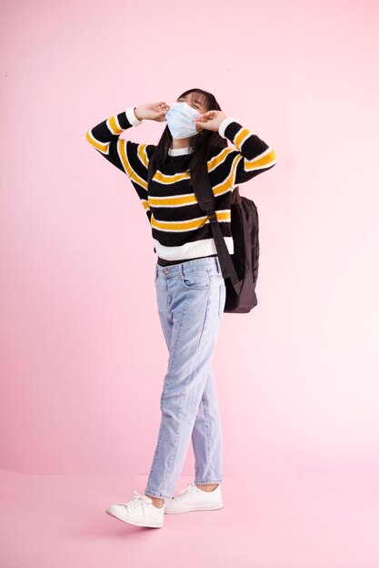 Student young girl wear mask on pink background.