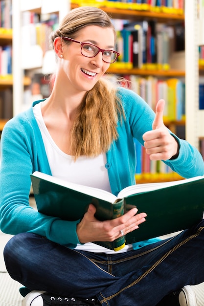 Student - young woman or girl sitting with books in library learning