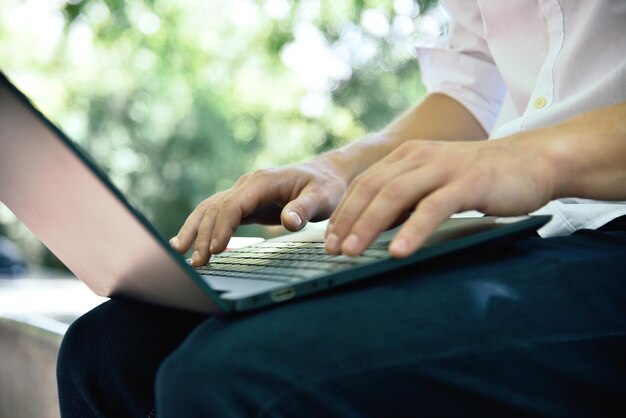 Student zit in het park en typt op laptop