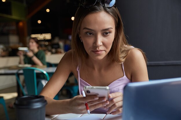 Student zittend aan tafel van coffeeshop studeren met laptop huiswerk maken