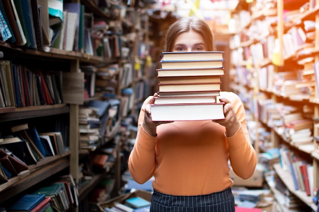 Studente houdt een stapel boeken in de bibliotheek