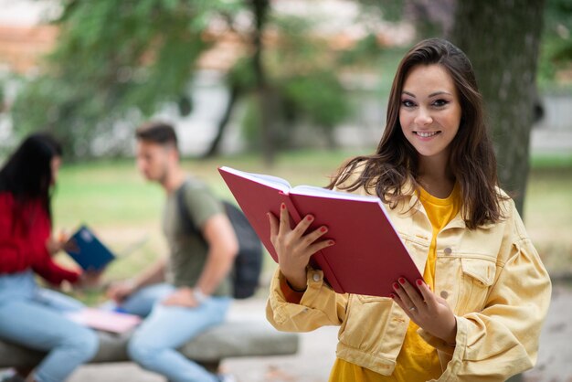 Studente met een boek vooraan een groep vrienden