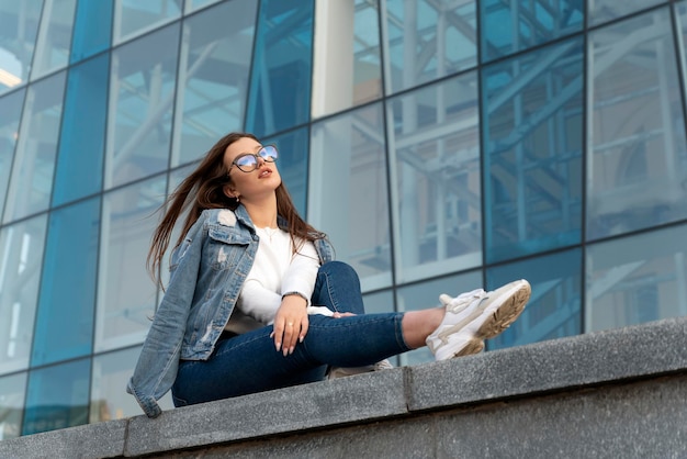 Studente rust op straat Jonge vrouw in modieuze jeugdkleding