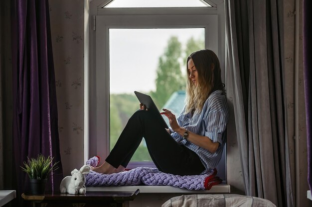 studente zit op de vensterbank in de slaapzaal en studeert in de tablet