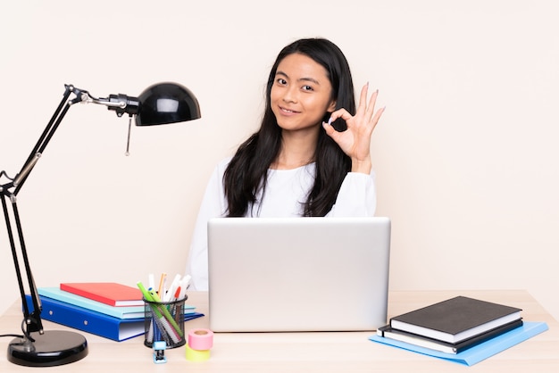 Studenten Aziatisch meisje in een werkplaats met laptop die op beige wordt geïsoleerd