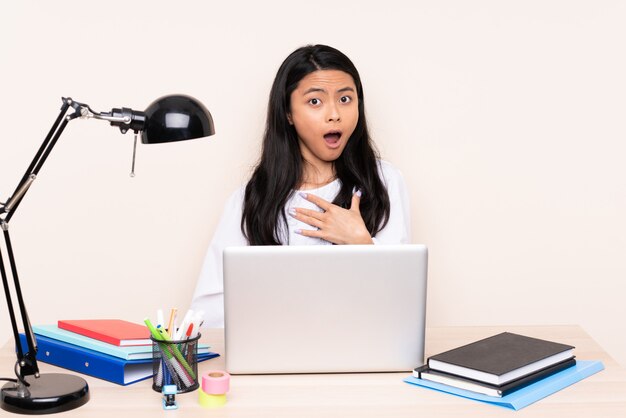 Studenten Aziatisch meisje in een werkplaats met laptop die op beige wordt geïsoleerd