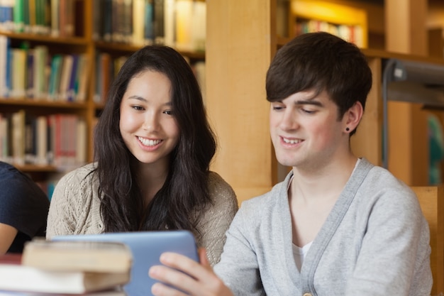 Studenten die bij de bibliotheek zitten die een tabletpc houden