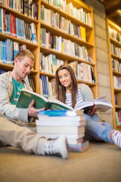 Studenten die boeken op de bibliotheekvloer lezen