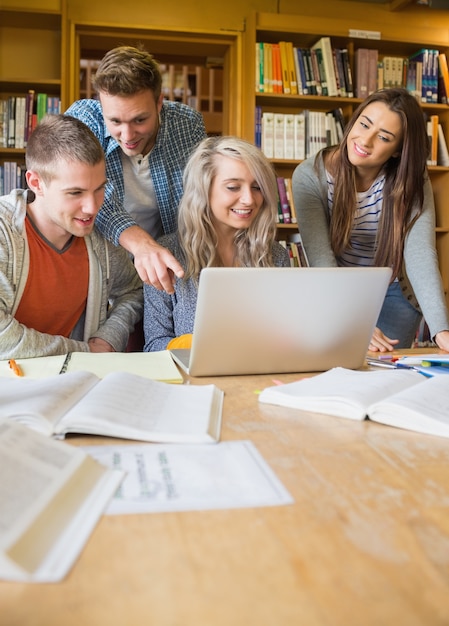 Studenten die laptop met behulp van bij bureau in bibliotheek