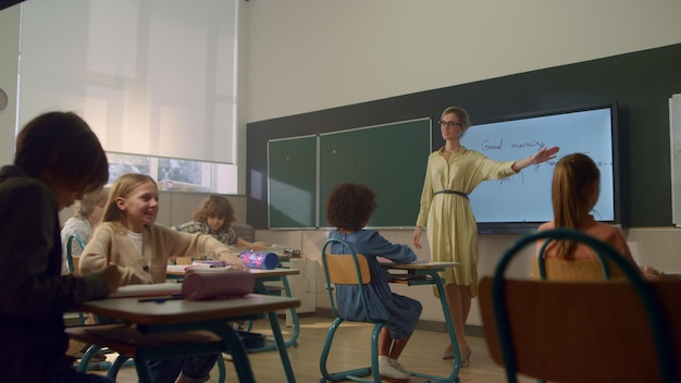 Studenten die op de basisschool leren Vrouwelijke lerares die voor het bord staat