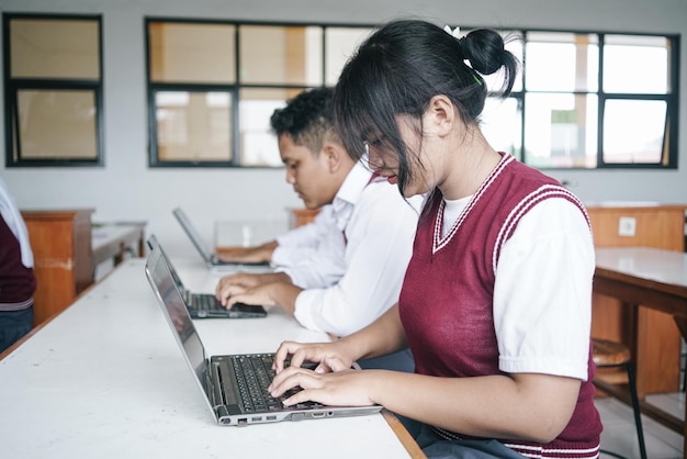 Studenten in uniform werken op een laptop in de klas.