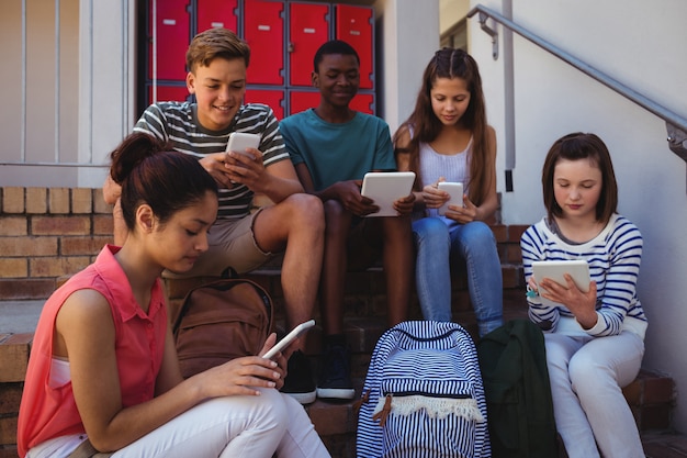 Studenten met behulp van mobiele telefoon en digitale tablet op trap