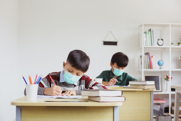 Studenten met een medisch masker studeren en doen opdrachten in de klas