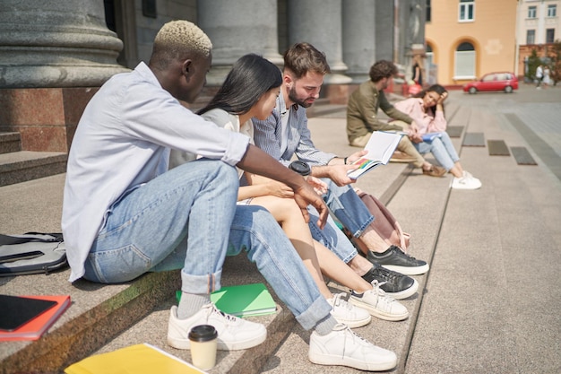 Studenten met handboeken die op de treden zitten