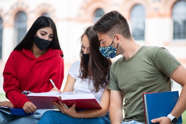 Studenten studeren samen op een bankje buiten en dragen maskers tijdens coronavirustijden