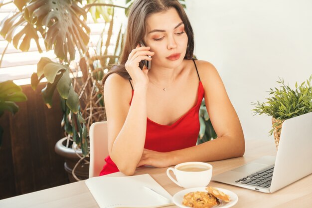 Studentenmeisje die de telefoon spreken terwijl het zitten in koffie