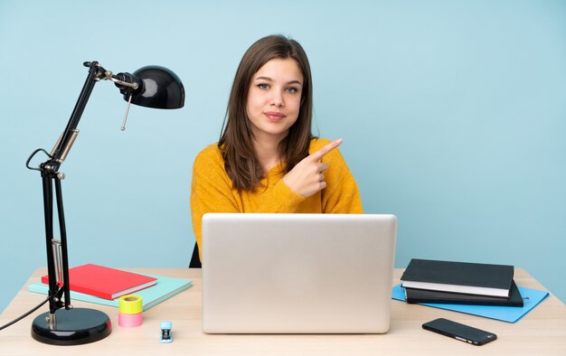 Studentenmeisje die in haar huis op blauw bestuderen die aan de kant richten om een product voor te stellen