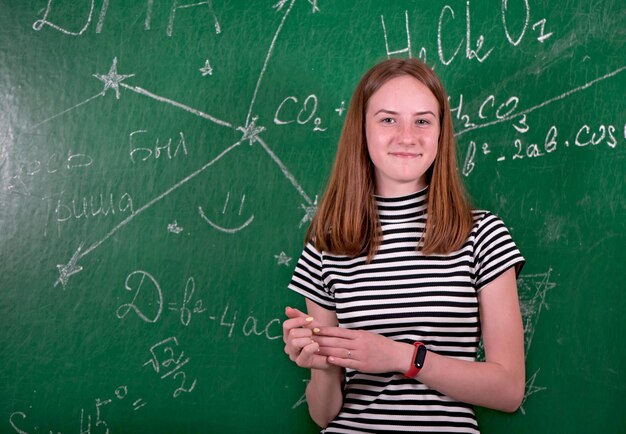 Studentenmeisje die zich dichtbij schoon bord in de klas bevinden