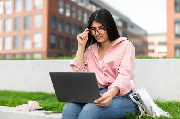 Studentenmeisje studeert buiten op een laptop.