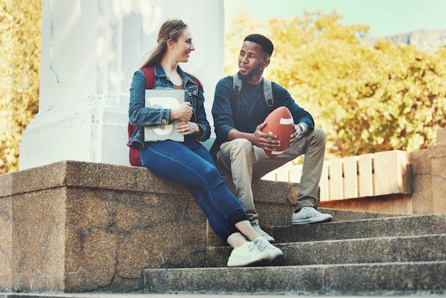 Foto studentenvrienden en praten of hechten op de universiteitscampus buiten voor kennis en onderwijs vrouw man en student mensen praten over schoolwerk en sport of voetbal